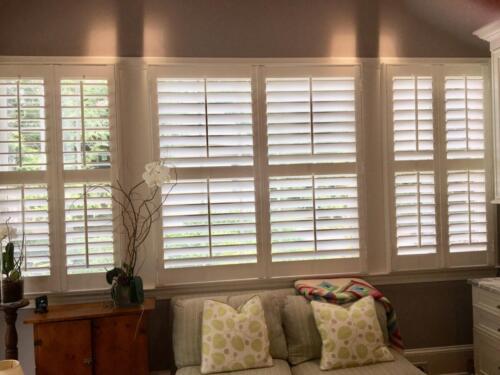 white_plantation_shutters_wide_behind_couch
